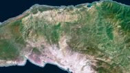 Satellite view of Haiti highlighting coastal areas and inland mountains.